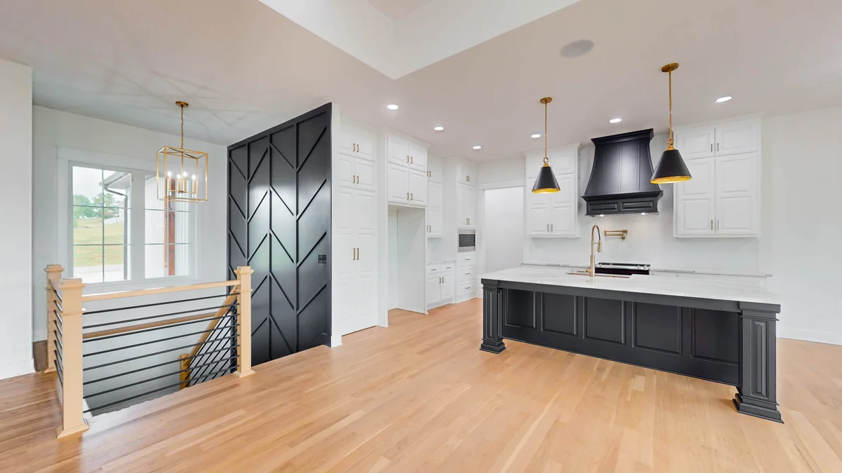 An eStar home interior with a black kitchen island, white cabinetry, and wood floors